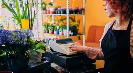 redhead-female-flower-seller-using-cash-register-market-shop.jpg